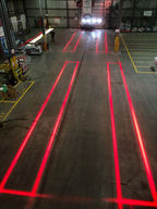 High-contrast red lines projected onto the warehouse floor to mark AGV lanes