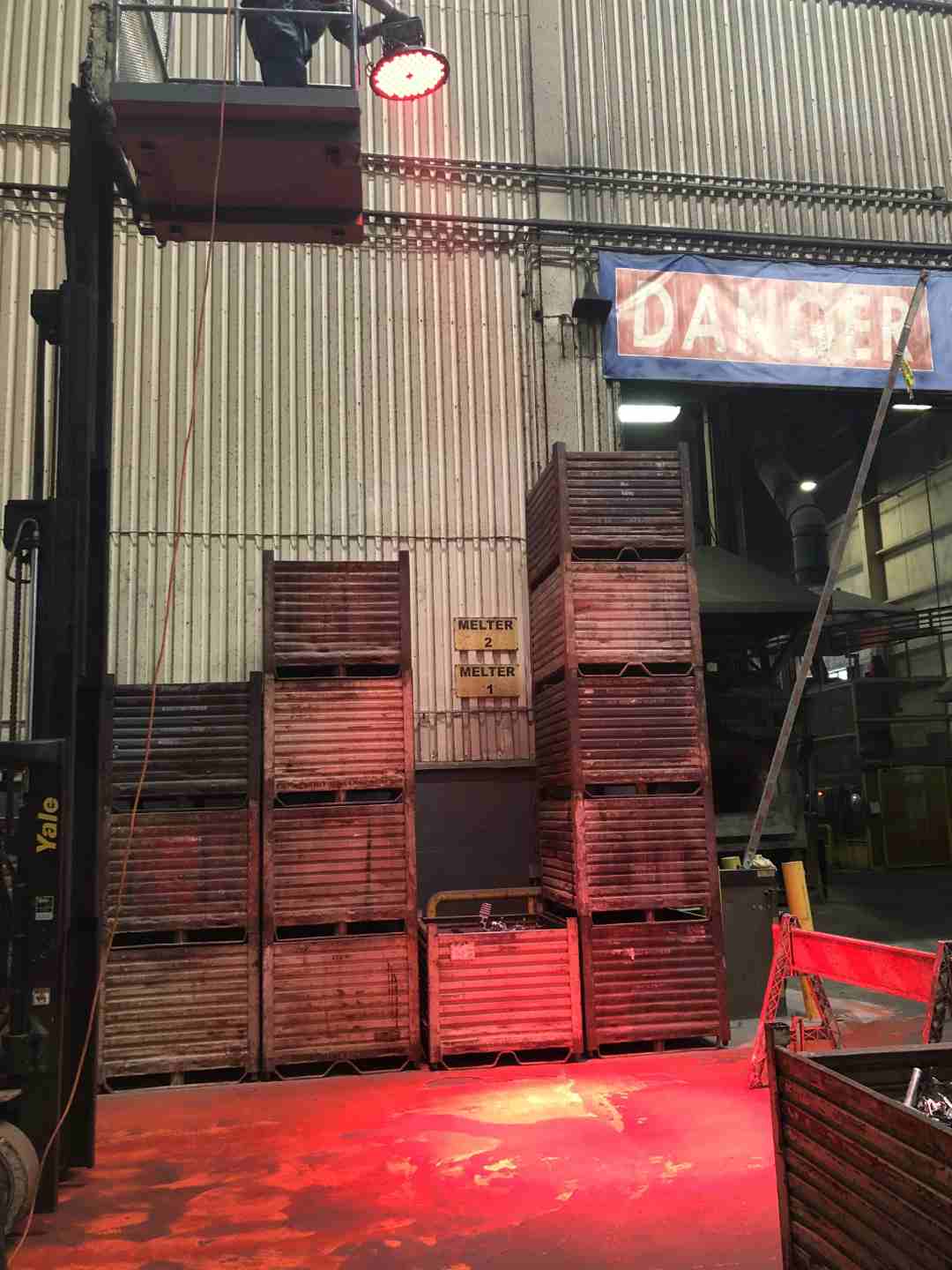 High-contrast red light projected onto the warehouse floor marking the position of the overhead crane load